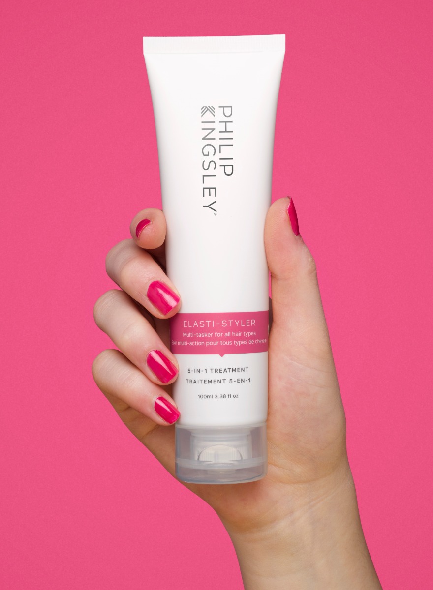 Hand holding the Philip Kingsley elasti-styler 5-in-1 treatment. Achieve shiny, smooth hair with our anti-frizz & conditioning serum.