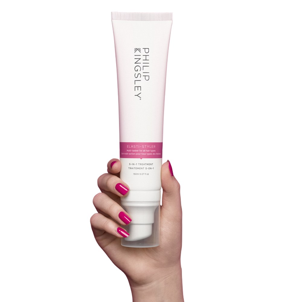 Hand holding the Philip Kingsley elasti-styler 5-in-1 treatment. Achieve shiny, smooth hair with our anti-frizz & conditioning serum.